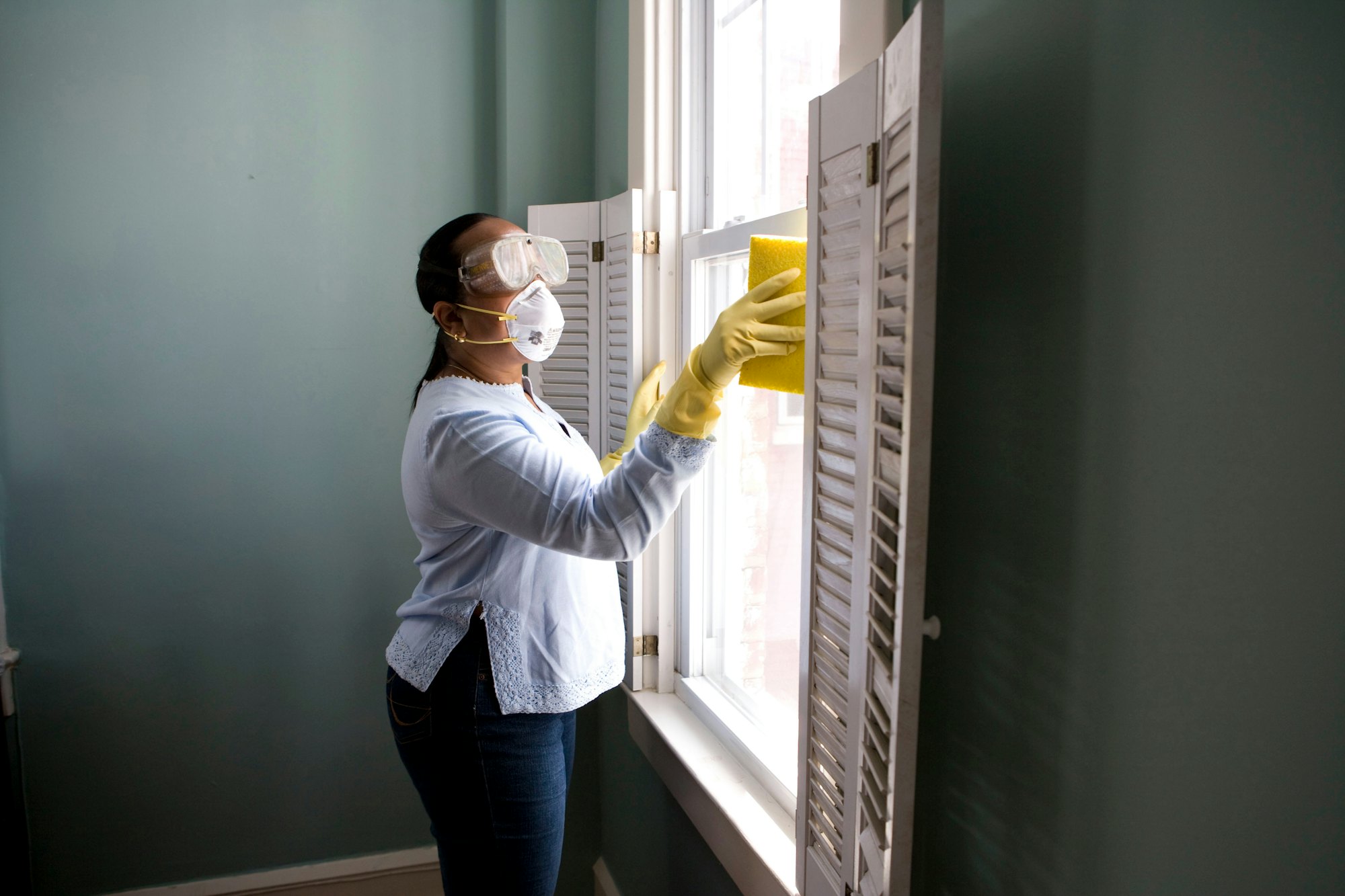 Custodian in protective gear cleaning a window