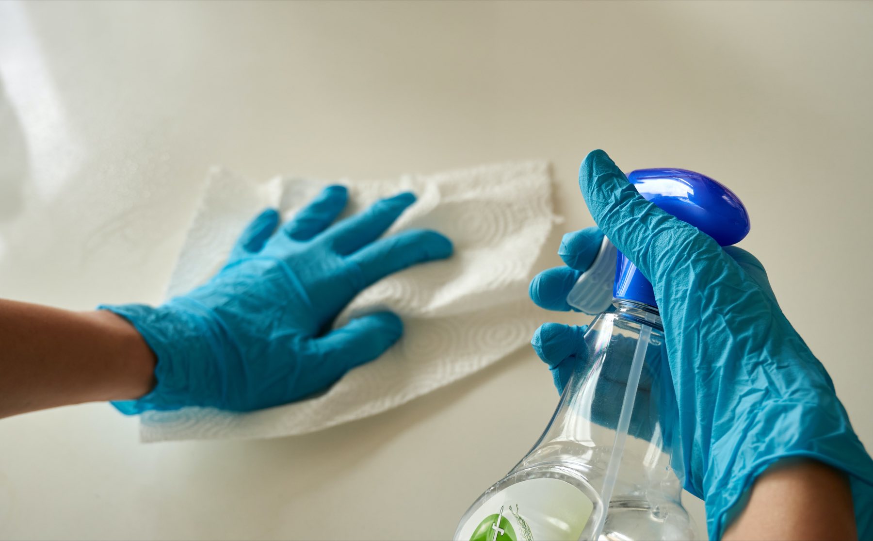 Gloved hands wiping a surface clean